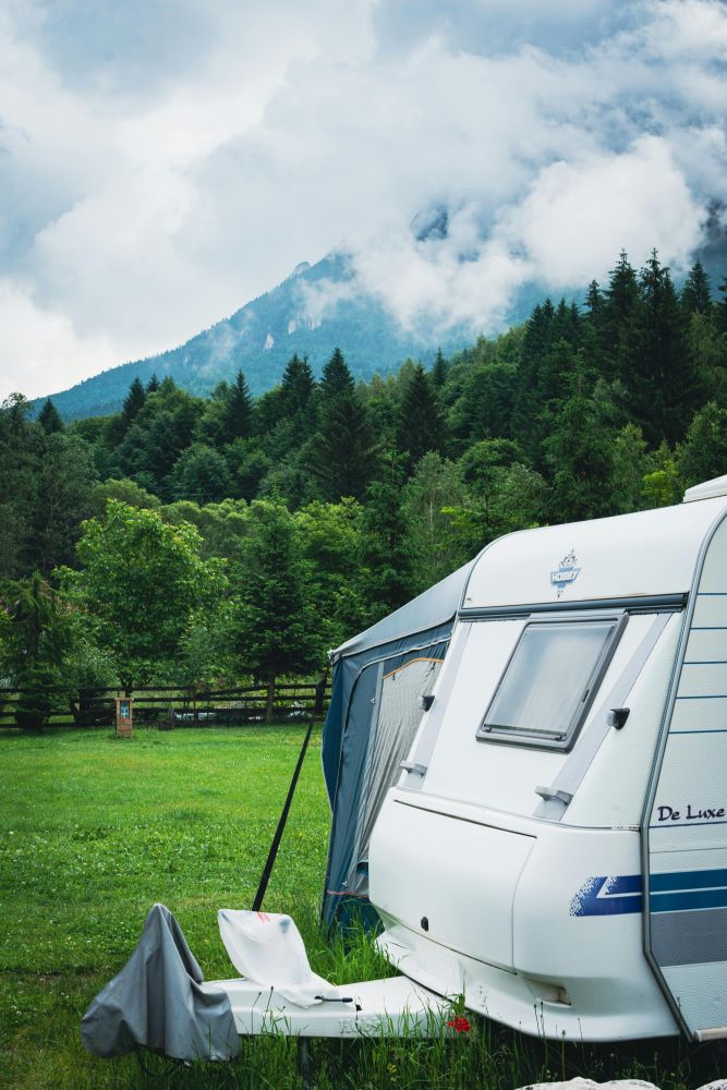 Witte caravan op een grasveld met bomen op de achtergrond